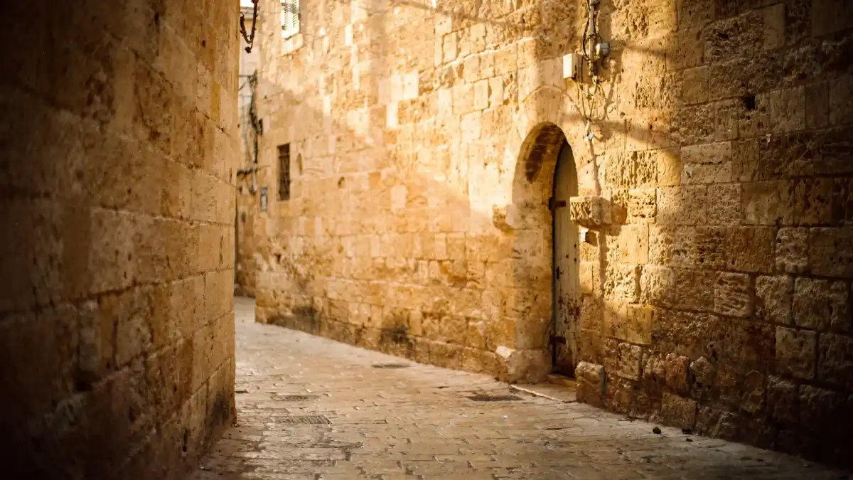 סמטה מאבן ירושלמית עם שער קמרון בעיר העתיקה בשעת אור זהוב